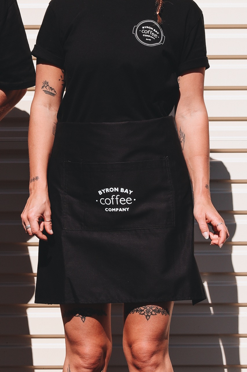 Girl wearing Byron Bay Coffee Co black apron